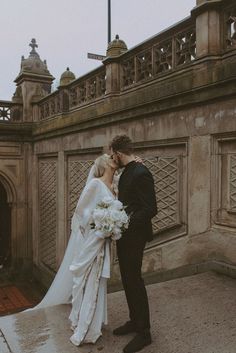 a bride and groom kissing in front of an old building