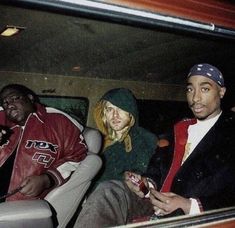 three people sitting in the back of a car with one person holding a cell phone