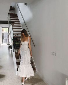 a woman in a white dress is walking up the stairs