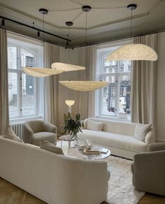 a living room filled with white furniture and lots of windows in it's walls