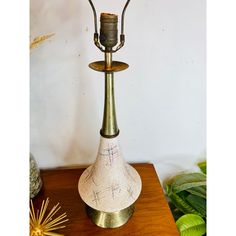 a table lamp sitting on top of a wooden table next to a potted plant