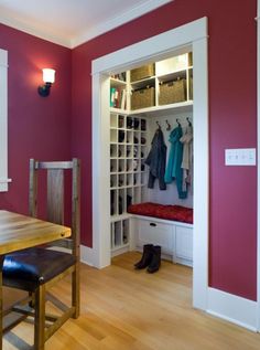 a dining room with a bench and coat rack in the corner next to a closet