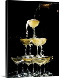 champagne being poured into wine glasses on top of a glass table with black background photo