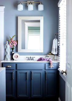 a bathroom with blue cabinets and white fixtures, along with a large mirror above the sink