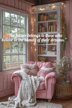 a pink couch sitting in front of a window next to a book shelf filled with books