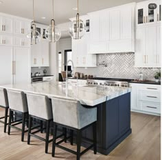 a large kitchen with white cabinets and marble counter tops, along with bar stools