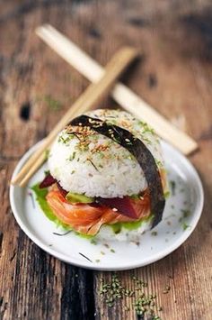 a white plate topped with sushi and rice on top of a wooden table next to chopsticks