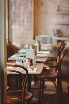 an empty restaurant with wooden chairs and tables in the foreground, there is no one sitting at the table