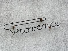 the word storence written in cursive writing on a concrete wall with rusted nails