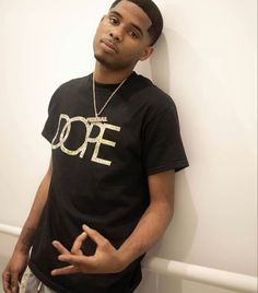 a young man leaning against a wall with his hands in the air while wearing a black t - shirt that says dope