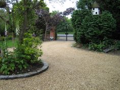 a gravel driveway surrounded by trees and bushes