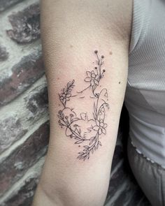 a woman's arm with flowers and leaves tattooed on the left side of her arm