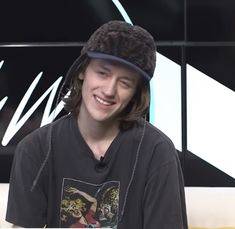 a young man wearing a hat while sitting down