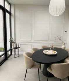 a dining room table with chairs and a plate on the table in front of large windows