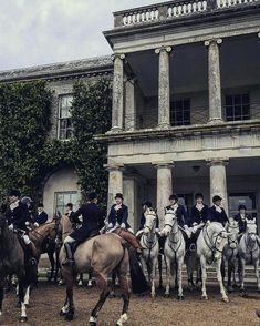 a group of men riding on the backs of horses in front of a large building