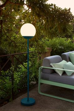 a blue floor lamp sitting on top of a patio next to a couch and chair