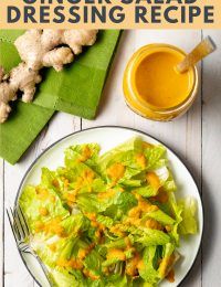 a white plate topped with lettuce next to a glass of orange juice and sliced ginger