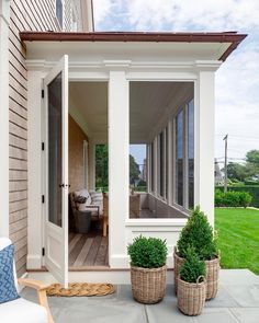 a porch with two planters on the side of it and an open door leading to another room