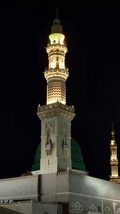 a tall white building with a clock on it's side and lights on at the top