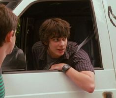 two young men sitting in the back of a truck looking at each other and talking