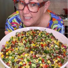 an old woman with glasses holding a large bowl of food in front of her face