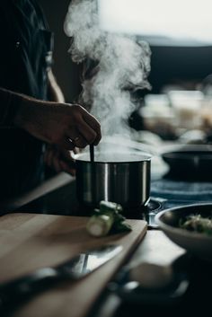 a person cooking in a kitchen with steam coming out of the pots and pans