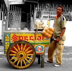 a man standing in front of a street vendor cart with bread on it's wheels