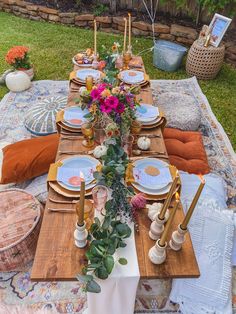 a table set up with plates and place settings for an outdoor dinner party in the backyard