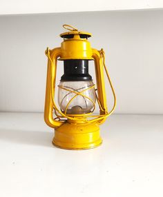 an old fashioned yellow lantern on a white surface