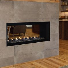 a modern fireplace in a living room with wood flooring and stone walls, lit by candles