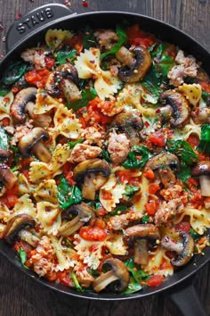 a skillet filled with pasta, mushrooms and spinach