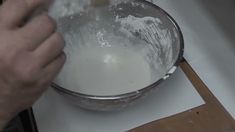 a person mixing something in a glass bowl