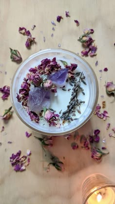 a bowl filled with flowers next to a candle