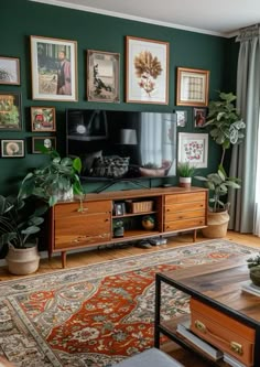 a living room with green walls and pictures on the wall, plants in vases