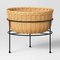 a wicker basket sitting on top of a metal stand with black legs and an iron base