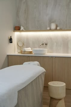 a white bed sitting next to a bathroom sink under a light on the side of a wall