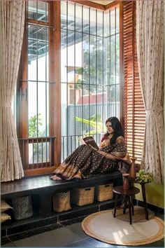 a woman is sitting on a window sill and reading a book while looking out the window