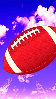 an american football flying through the air with clouds in the backgrouund and blue sky