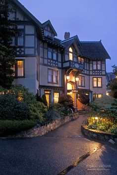 a large house with lots of windows and lights on it's front entrance at night