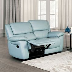 a light blue leather reclining sofa sitting on top of a wooden floor next to a white rug