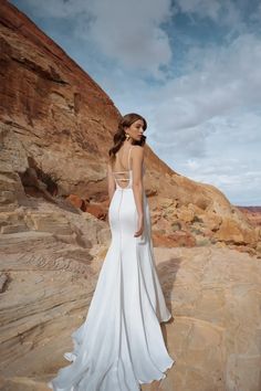 a woman in a white dress standing on rocks