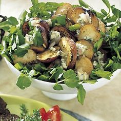 a salad in a white bowl on top of a table next to other plates and utensils