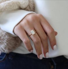 a woman's hand wearing a gold ring with a square shaped diamond on it