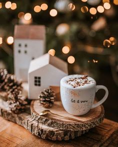 a cup of hot chocolate sitting on top of a wooden table next to a christmas tree