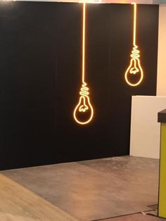 three light bulbs are hanging from the ceiling in an office setting with black walls and flooring