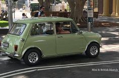 an old green car is driving down the street