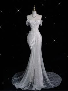 a white wedding dress on display in front of a black background with stars and sparkles