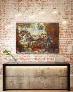 a painting hanging on the wall above a desk in a room with brick walls and lights