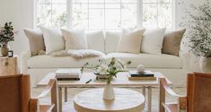 a living room filled with furniture and flowers on top of a coffee table in front of a window