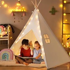 two children are sitting in a teepee reading a book with lights on the wall behind them